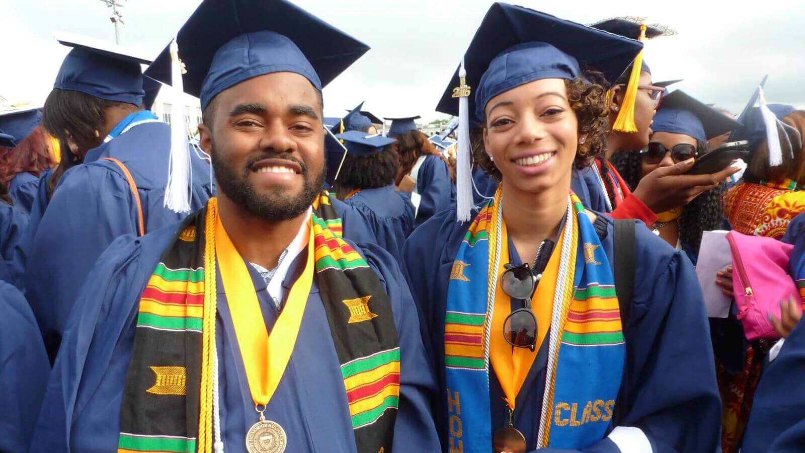 Two students wearing graduation garb at an event