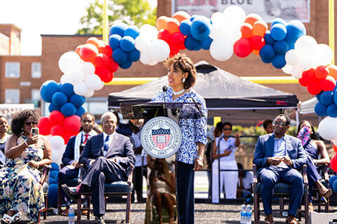 Person giving a speech on a festive stage decorated with balloons in Howard colors.