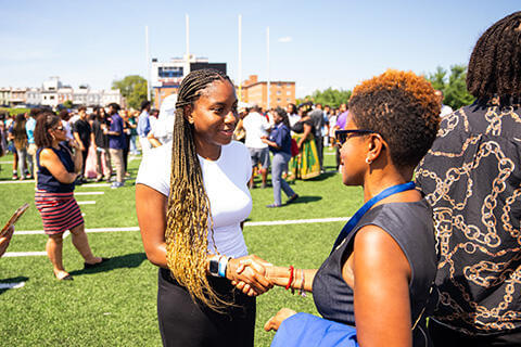 Student shaking hands with Howard staff on the field at Greene Stadium
