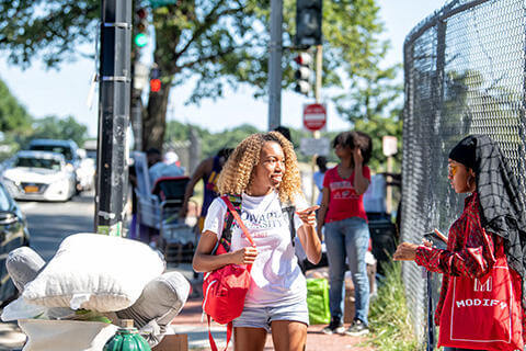 Howard students talking and smiling as they move in to a dorm on campus